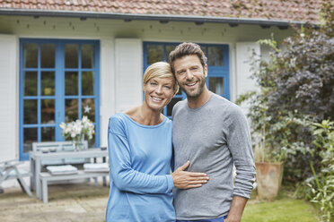 Portrait of smiling couple standing in front of their home - RORF01414