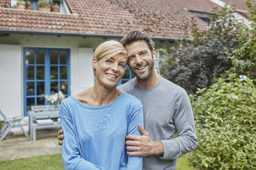 Portrait of smiling couple standing in front of their home - RORF01418