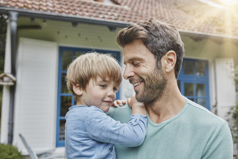 Glücklicher Vater mit Sohn vor ihrem Haus, lizenzfreies Stockfoto