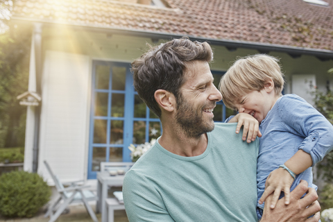 Glücklicher Vater mit Sohn vor ihrem Haus, lizenzfreies Stockfoto