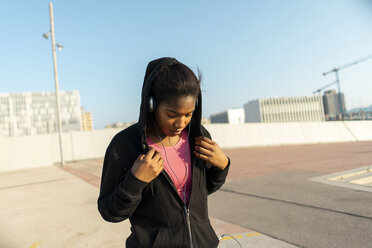 Junge sportliche Frau hört Musik mit Kopfhörern - AFVF01342