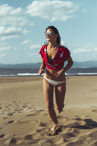 Porträt eines lachenden Teenagers, der am Strand läuft, lizenzfreies Stockfoto