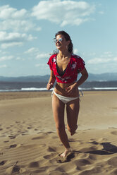Portrait of laughing teenage girl running on the beach - ACPF00158