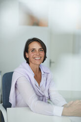 Portrait of mature businesswoman sitting at desk in an office - PNEF00843