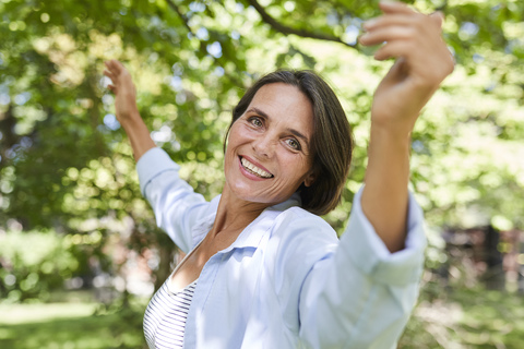 Porträt einer lächelnden reifen Frau, die in der Natur tanzt, lizenzfreies Stockfoto