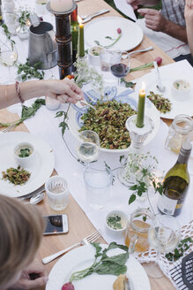 Menschen um einen Tisch bei einer Gartenparty, eine Schüssel Salat. - MINF06019