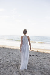 Blonde Frau in einem langen Kleid an einem Sandstrand. - MINF06025