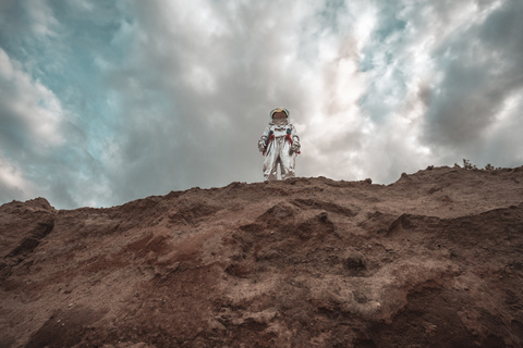 Spaceman standing on slope of nameless planet stock photo
