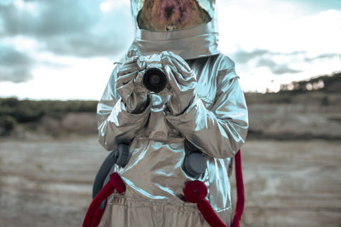 Spaceman on nameless planet taking pictures with camera stock photo