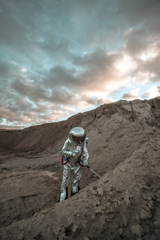 Raumfahrer auf einem namenlosen Planeten, der den Boden untersucht, lizenzfreies Stockfoto
