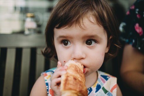 Porträt eines kleinen Mädchens, das ein Croissant isst - GEMF02242