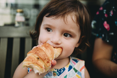 Porträt eines kleinen Mädchens, das ein Croissant isst - GEMF02243