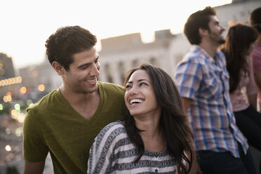 A small group of friends gathered on a rooftop terrace overlooking a city at twilight. - MINF06059