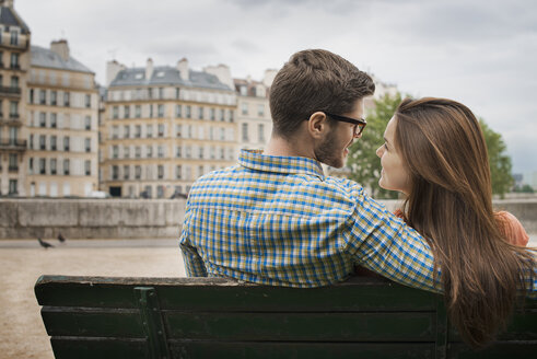 Ein Paar, Mann und Frau, sitzen eng beieinander auf einer Bank am Ufer der Seine. - MINF06072