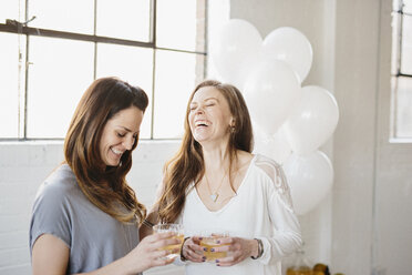 Zwei Frauen stehen nebeneinander und halten Getränke, weiße Luftballons, Partydekoration. - MINF06092