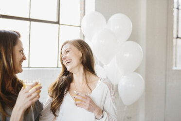 Zwei Frauen stehen nebeneinander und halten Getränke, weiße Luftballons, Partydekoration. - MINF06094