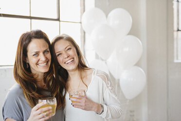 Zwei Frauen stehen nebeneinander und halten Getränke, weiße Luftballons, Partydekoration. - MINF06095