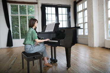 Young woman playing on a grand piano in a rehearsal studio. - MINF06112