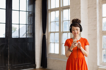 Young woman wearing headphones, standing in a rehearsal studio, listening to music. - MINF06123