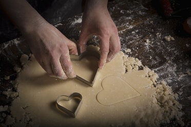 Backen zum Valentinstag, Frau sticht herzförmige Kekse aus dem Teig aus. - MINF06185