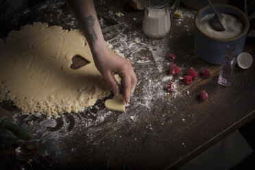 Backen zum Valentinstag, Frau sticht herzförmige Kekse aus dem Teig aus. - MINF06186