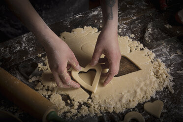 Backen zum Valentinstag, Frau sticht herzförmige Kekse aus dem Teig aus. - MINF06187