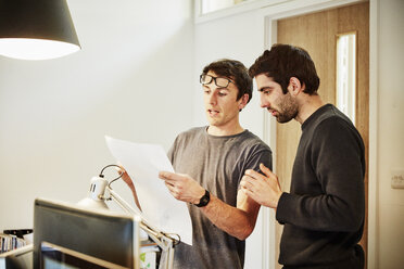 A furniture workshop making bespoke contemporary furniture pieces using traditional skills in modern design. Two people discussing a design, referring to drawings and laptop computers. - MINF06232