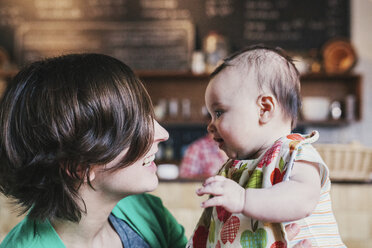 Eine Mutter und ihr kleines Baby schauen sich lächelnd in einem Café an. - MINF06235