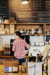 Eine Frau, die hinter dem Tresen eines Cafés arbeitet, Geschäftsinhaberin. - MINF06238