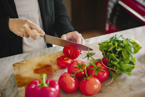 Eine Frau schneidet mit einem scharfen Messer Tomaten. - MINF06249