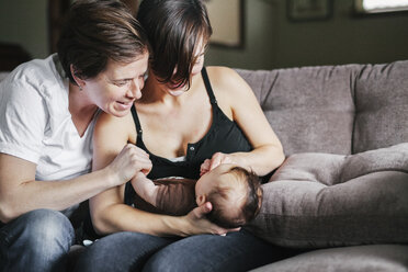 A same sex couple two women playing with their 6 month old baby  