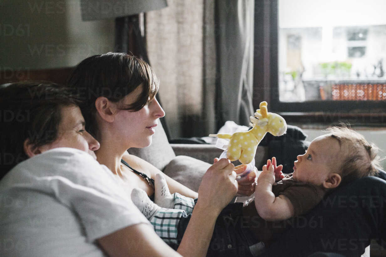 A same sex couple, two women playing with their 6 month old baby girl.  stock photo