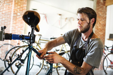 Ein Mann arbeitet in einer Fahrradwerkstatt und überprüft den Rahmen eines Fahrrads. - MINF06286