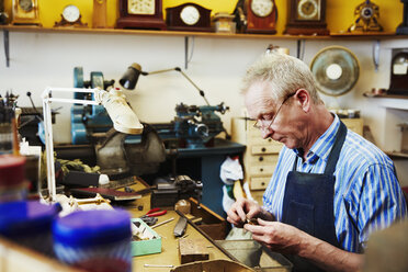 Ein Uhrmacher bei der Reparatur von Kleinteilen einer Uhr. - MINF06320