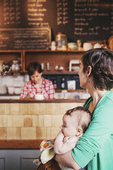 Zwei Frauen, ein gleichgeschlechtliches Paar mit ihrem 6 Monate alten Baby in ihrem Café. Geschäftsinhaber und Eltern. - MINF06329