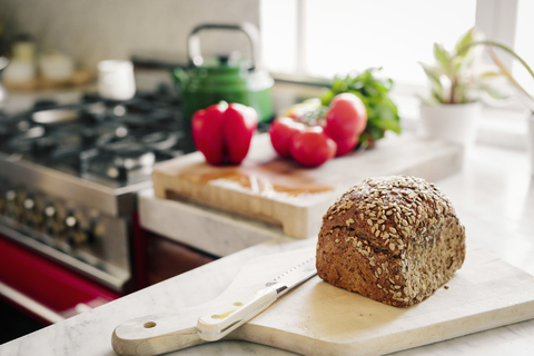 Ein frischer Laib gebackenes Schwarzbrot auf einem Brett mit einem Brotmesser., lizenzfreies Stockfoto