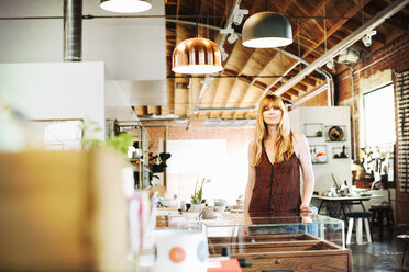 Woman with long blond hair standing in a shop, smiling at the camera. - MINF06395