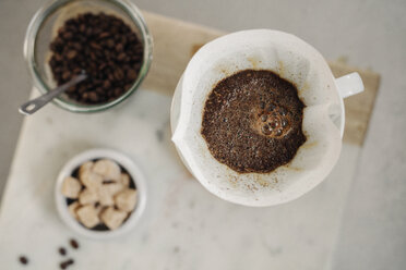 Zubereitung von Filterkaffee: Blick von oben auf gemahlenen Kaffee, Papierfilter und Würfelzucker. - MINF06422