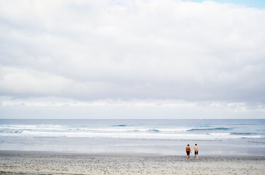 Zwei Männer stehen an einem Sandstrand am Meer. - MINF06455