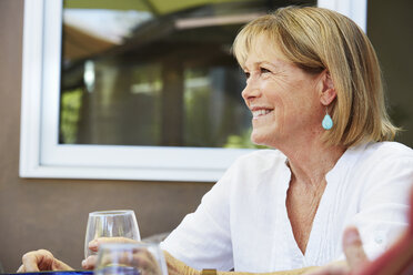 Smiling senior woman with blond hair sitting outdoors. - MINF06463