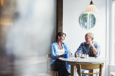 Zwei Personen sitzen an einem Kaffeetisch, der Vordergrund ist unscharf. - MINF06470