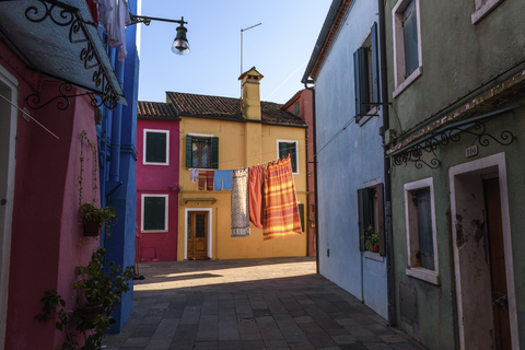 Enge Gasse mit bunten Fassaden und Wäsche auf der Wäscheleine in Venedig, Italien., lizenzfreies Stockfoto