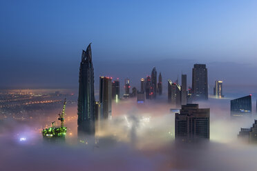 Blick auf beleuchtete Wolkenkratzer über den Wolken in Dubai, Vereinigte Arabische Emirate. - MINF06520
