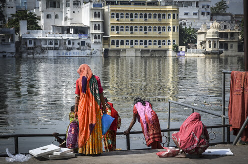 Women in colourful saris standing on the lake shore in Udaipur. - MINF06529