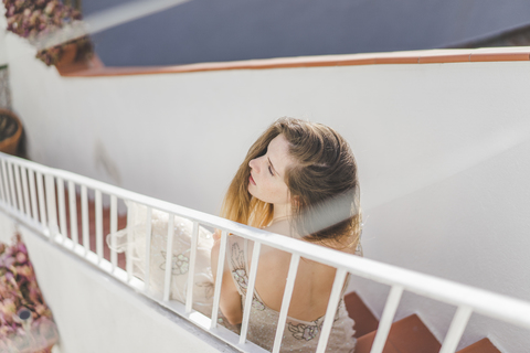 Junge Frau im Hochzeitskleid, auf einer Treppe sitzend, lizenzfreies Stockfoto