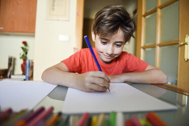 Portrait of smiling little girl drawing with coloured pencils at home - JSMF00383