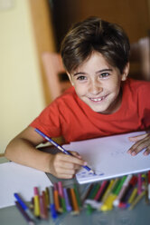 Porträt eines lächelnden kleinen Mädchens, das zu Hause mit Buntstiften zeichnet - JSMF00384