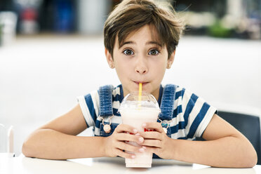 Porträt eines kleinen Mädchens, das einen Erdbeermilchshake in einem Straßencafé trinkt - JSMF00410