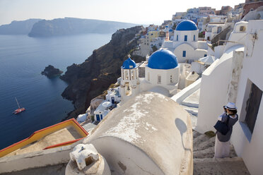 Blick von oben auf eine traditionelle weiß getünchte Kirche mit leuchtend blauer Kuppel auf der Insel Santorin, Griechenland. - MINF06573