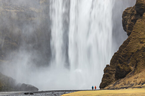 Landschaft mit Rückansicht einer Person, die neben einem hohen Wasserfall steht. - MINF06580